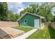 Green detached garage with a small wood deck, grassy area, and white door at 1122 W 35Th St, Indianapolis, IN 46208