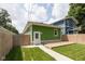 Backyard view of a green detached garage with wood fence, deck, and blue house in background at 1122 W 35Th St, Indianapolis, IN 46208
