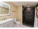 Modern bathroom featuring black marble shower with gold fixtures and a white vanity with lit mirror at 1122 W 35Th St, Indianapolis, IN 46208