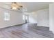 Bright living room featuring modern gray wood flooring, neutral paint, ceiling fan and an exterior access door at 1511 E 20Th St, Muncie, IN 47302