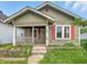 Close-up of home exterior showing the front porch with peeling paint and overgrown garden at 1550 Hoefgen St, Indianapolis, IN 46203
