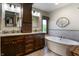 Bathroom with double vanity, granite countertops, dark wood cabinets, soaking tub, and tile accents at 160 Scranton Ct, Zionsville, IN 46077