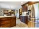 A spacious kitchen featuring stainless steel appliances, wooden cabinetry, and an island counter with an open view to the living area at 160 Scranton Ct, Zionsville, IN 46077