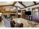 Comfortable living room featuring wood beams, hardwood floors, a brick fireplace, and dark leather furniture at 160 Scranton Ct, Zionsville, IN 46077