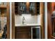 Close up view of a wet bar, complete with sink, mini-fridge, custom cabinets and a tile backsplash with under cabinet lighting at 160 Scranton Ct, Zionsville, IN 46077