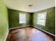 Green bedroom filled with natural light and hardwood floors, offering potential for rejuvenation at 1601 E 44Th St, Indianapolis, IN 46205