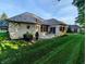 Brick home featuring a backyard with a well-kept lawn, a patio, and lush greenery at 16254 Quartz Dr, Noblesville, IN 46060