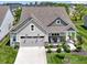 Aerial front view of a charming home featuring a two-car garage, landscaped lawn, and cozy front porch with rocking chairs at 19959 Cowie Ln, Westfield, IN 46074