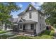 Charming two-story home featuring a covered front porch, classic white siding, and lush landscaping at 2001 S Jefferson St, Muncie, IN 47302