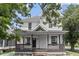 Charming two-story home featuring a covered front porch and classic white siding with lush landscaping at 2001 S Jefferson St, Muncie, IN 47302