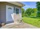 A charming, green backyard view with a door, window, and small outdoor table and chairs set on concrete slab at 2020 Rosedale Dr, Indianapolis, IN 46227