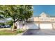 Beige townhome featuring an attached garage, a mature tree, and a well-maintained lawn at 2259 Colfax Ln # 2259, Indianapolis, IN 46260