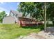 Backyard featuring a red wooden deck, storage shed, mature trees, and a well-manicured lawn at 3067 Stilton Dr, Cicero, IN 46034