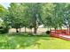 Lush backyard with green lawn, mature trees, and a red wooden deck at 3067 Stilton Dr, Cicero, IN 46034