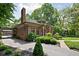 Brick home with a green tile roof, driveway, and well-manicured landscaping at 4455 Broadway St, Indianapolis, IN 46205