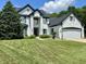 Beautiful two-story white brick home with a lush green lawn, mature trees, and attached garage at 4655 Rockcress Ct, Zionsville, IN 46077