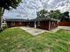 Backyard view of the brick ranch style home with a concrete patio and green lawn at 5015 Nowland Ave, Indianapolis, IN 46201
