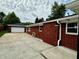 Rear exterior of a brick home with a detached two-car garage and driveway at 5015 Nowland Ave, Indianapolis, IN 46201