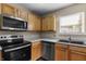 Compact kitchen features stainless steel appliances, wooden cabinets, and a black sink at 5519 Apple Branch Way, Indianapolis, IN 46237