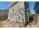 View of the side of the home with horizontal siding, gravel, and brick foundation at 555 N Oakland Ave, Indianapolis, IN 46201