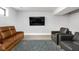 Living room with neutral walls, plush carpet, brown leather sofa, grey accent chair, and mounted tv at 5678 N College Ave, Indianapolis, IN 46220