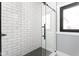 Contemporary shower design with hexagon-tiled floor, subway tile, and a sleek black shower door at 5678 N College Ave, Indianapolis, IN 46220