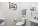 A well-lit powder room with a white toilet and sink and decorative artwork at 5832 Buskirk Dr, Indianapolis, IN 46216