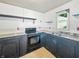 Kitchen with black cabinetry, black appliances, and a double basin sink, ripe for renovation at 637 Olin Ave, Indianapolis, IN 46222