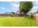 Expansive backyard showcasing a well-kept lawn, deck, mature tree, and secure fencing at 662 Leah Way, Greenwood, IN 46142