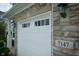 Close-up view of the garage door showing the house number, with stone and carriage lights at 7147 Prelude Rd, Brownsburg, IN 46112