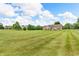 Spacious backyard with a well-maintained lawn, brick home, patio seating, and mature trees at 7304 E Stop 11 Rd, Indianapolis, IN 46259