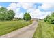 Long driveway leading up to a single Gathering home with a well-maintained lawn and mature trees at 7304 E Stop 11 Rd, Indianapolis, IN 46259