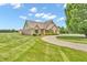 Attractive brick home with lush green lawn and mature trees, showcasing the well-maintained property at 7304 E Stop 11 Rd, Indianapolis, IN 46259