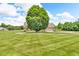 Brick home with a large front yard, shade tree and outbuilding for storage at 7304 E Stop 11 Rd, Indianapolis, IN 46259