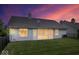 Backyard view featuring a screened-in porch, well-maintained lawn, and a beautiful sunset sky at 8213 Thoroughbred Run, Indianapolis, IN 46256