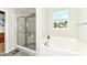 Bathroom with a large tub, glass-enclosed shower, and a window overlooking the backyard at 8864 Rowling Way, Indianapolis, IN 46239