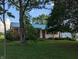 Charming ranch-style home with a green metal roof, featuring a well-manicured lawn and mature trees at 8923 Maze Rd, Indianapolis, IN 46259