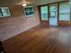 Spacious sunroom with wood paneled walls and ceiling, hardwood floors, and several windows offering views of greenery at 8923 Maze Rd, Indianapolis, IN 46259