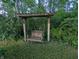 A charming wooden swing hanging beneath a pergola, nestled within a lush green garden at 8923 Maze Rd, Indianapolis, IN 46259