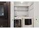 Convenient laundry room featuring white appliances, open shelving, and patterned wallpaper at 911 Glendale Dr, Lebanon, IN 46052