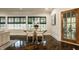 Sunlit dining area with modern chairs, glass table, and dark wood flooring next to a stylish wooden door at 110 Bow Ln, Indianapolis, IN 46220