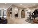 Grand foyer with travertine floors, arched doorways, custom iron door, and grand piano at 110 Bow Ln, Indianapolis, IN 46220
