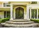 Elegant front entrance with stone steps, a decorative iron door, and meticulously landscaped surroundings at 110 Bow Ln, Indianapolis, IN 46220