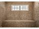 Elegant shower with neutral toned tile, built in bench, and window providing natural light at 110 Bow Ln, Indianapolis, IN 46220