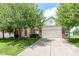 Charming brick home with a two-car garage and mature trees in a well-kept lawn and blue skies overhead at 11820 Stepping Stone Dr, Fishers, IN 46037