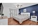 Bedroom with wood floor, ceiling fan, a large window, and stylish decor, including a navy accent wall at 1481 Wrenwood Dr, Columbus, IN 47201