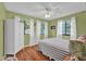 Bedroom featuring hardwood flooring, a ceiling fan, three windows, and an armoire against a green wall at 1481 Wrenwood Dr, Columbus, IN 47201