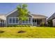 The backyard features well-maintained lawn, a gray exterior, black framed windows, a brick accent wall, and green shrubs at 15600 Woodford Dr, Westfield, IN 46074