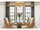 Dining room with marble table, upholstered chairs, a decorative vase, and modern chandelier beneath black frame windows at 15600 Woodford Dr, Westfield, IN 46074