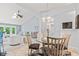 Open-concept dining area with a glass table set for four, seamlessly flowing into the adjacent living room at 1605 Leisure Way, Greenfield, IN 46140